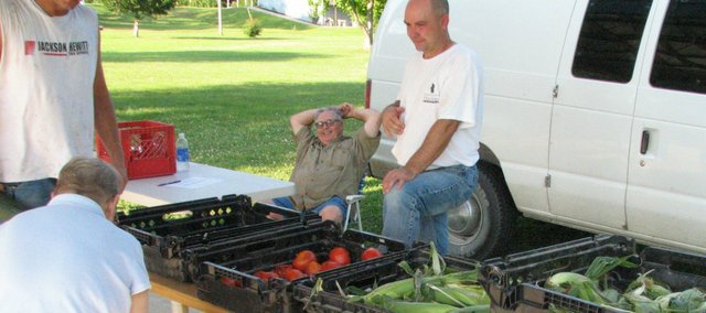 Brian Habjan, community coordinator for the Prison Garden Project, helps some Linwood residents as they look at tomatoes and zucchini grown at the United State Penitentiary in Leavenworth.