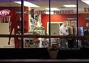 A Johnson County Sheriff's Office crime scene technician documents evidence inside the store around 3 a.m. Saturday. Bullet holes and evidence markers can be seen in the front window.
