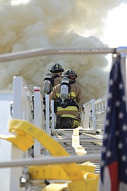 Shawnee firefighters scale the ladder of Truck 71 to access a window on the upper level of the home.