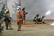 Three Shawnee firefighters and an Overland Park Fire battalion chief work the fire from the back side of the home.