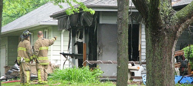 Shawnee firefighters look on at the damage from a house fire Thursday morning in Shawnee that killed two.