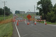 Basehor Public Works trucks are parked near the road closed signs on Parallel Road, where sinkholes (surrounded by orange netting) developed during Monday evening's storms.