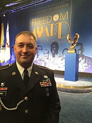 Army Reservist Sgt. 1st Class and Shawnee firefighter Douglas Simms stands in front of the the Freedom Award at the Pentagon last week. Simms nominated Shawnee for the award earlier this year.
