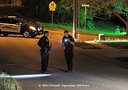 Two officers stand in the 10900 block of West 49th Street checking for any evidence after someone fired shots into an occupied duplex.