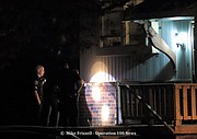 Police examine bullet holes in the siding of a duplex in the 10900 block of West 49th Street early Sunday morning.