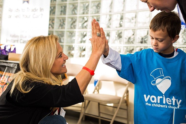 A Variety child gives executive director Deborah Wiebrecht a high five. He is one of hundreds of Kansas City area kids positively affected by the charity.