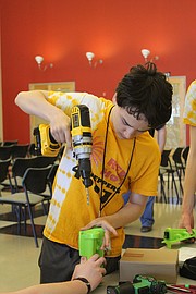 Kieran Roos, 13, helps modify a Power Wheels car for Parker, an Overland Park 4-year-old on Saturday morning.