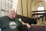 Monticello Community Historical Society president Terry Love poses next to a replica of a frontier wagon at the society’s museum in Lenexa. The museum features dozens of historical artifacts from Monticello’s heyday.