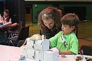 Camp Invention regional program managER Laura Leibman assists 8-year-old Danny Dolan, of Fairway, during the “Mod My Mini Mansion” class. To build their futuristic homes, the campers used unconventional materials, such as pipe cleaner, straws, tin foil, cellophane and cardboard boxes.