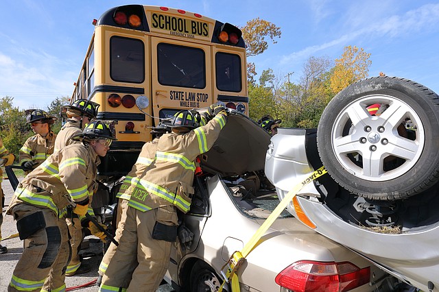 Shawnee firefighters peel back the roof of a vehicle to remove a dummy that was trapped in the simulated crash with a school bus.