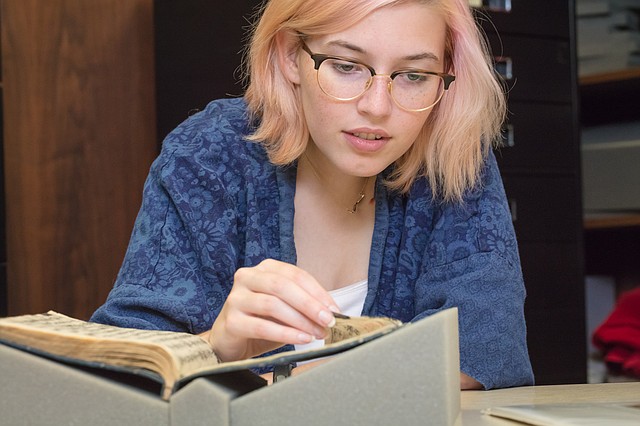 University of Arkansas honors student Claire Hutchinson looks at one volume in a 14-volume history of the Han Dynasty at Mullins Library on campus.