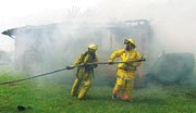 Firefighters stretch a hose toward the home west of Baldwin that
was destroyed by fire Thursday afternoon.