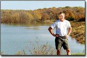 Kill Creek Regional Park Manager Monte Fiegel stands on the dam
that backs up a 28-acre lake that is now being stocked with fish.
Johnson County Park and Recreation District plans to open the
860-acre park in the late summer or early fall of 2001.