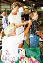 Alex Cox, 8, gets some help pinning his exhibitor number on before
the bucket calf show last Wednesday from his grandma, Lorene Cox,
seated and aunt, Sheri Flory.