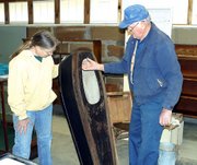 Susy Ross and Del Englen try to decide how to display an antique
child's coffin. The unused coffin and other mortuary antiques,
which were donated by Quisenberry Funeral Chapel, will be displayed
together.
