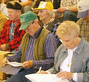 Hank Haller, pictured center in yellow cap, watches the cows he
bottle fed as calves being sold at Thursday's auction at the Holton
dairy farm south of Tonganoxie. Haller, who has lived and worked
with the Holtons for 65 years, said he understood the economic
reasons, but wished the herd didn't have to be split up.