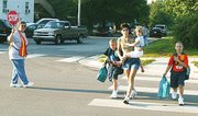 Tyler Hammond, left, and Sean Hammond, far right, cross the street
beside Tonganoxie Elementary School on Tuesday morning at the start
of the first day of school. Accompanying the boys are their mother,
Cheryl Macek, and sister, Madison Macek. School crossing guard
Helen McBroom holds a stop sign.