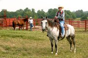 John Smith rides a horse at Tailgate Ranch. Pictured in the
background with another horse is ranch manager Kirk Sours. Smith
said it felt "normal" to be on a horse again.
