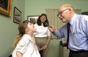 "Dr. Phil," as many of his patients call him, checks out the throat
of fourth generation patient Danielle Irwin while her mother
Elizabeth watches the proceedings.